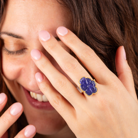 Carved tanzanite flower ring on model who is laughing