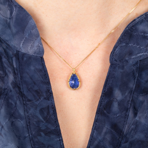 Blue tanzanite teardrop on model blue shirt