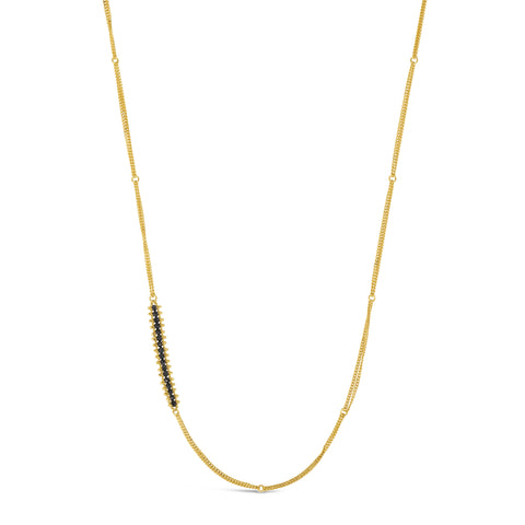 This long gold chain features a row of woven black diamonds beads stationed off-center. The necklace is finished with a lobster clasp