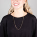 A model wears a long 18k yellow gold chain necklace that features an off-center row of woven champagne diamond beads.  