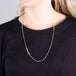 A model wears a long 18k yellow gold chain necklace that features an off-center row of woven silver diamond beads.
