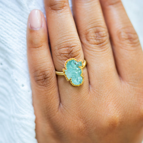A model wears an aquamarine seahorse ring in 18K yellow gold, hand-carved from the calming gemstone. Set in a meticulously handmade gold frame with delicate braided gold accents. Handmade in New York. 