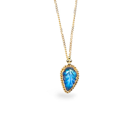 Hand-carved leaf pendant from a glowing blue Moonstone, encased in a unique handmade gold bezel with braided detail. Suspended on an 18k yellow gold chain, offering meticulous craftsmanship and elegance. Handmade in New York.