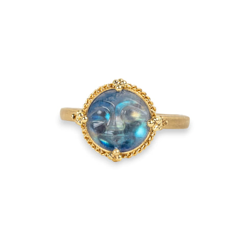 Moonstone ring in 18K yellow gold, expertly carved to depict a playful man on the moon with a jubilant expression. Set in a handmade gold setting accented with braided gold and granulated prongs. 