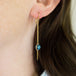 A model wears a long London blue topaz earring suspended in 18k yellow gold chain.