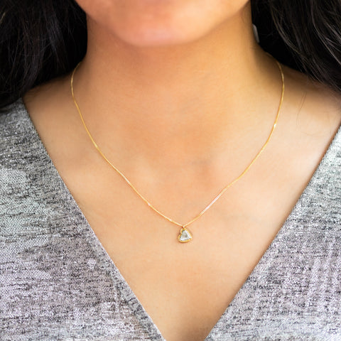 A model wears a heart-shaped diamond pendant on an 18K yellow gold chain. Handmade gold bezel with braided detail and granulation. Handmade in New York.