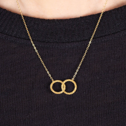 A close up of an 18k yellow gold interlocking circle necklace made with a diamond cut chain.