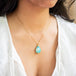 A model wears this Ethiopian Opal pendant on an 18K yellow gold chain. Meticulously crafted gold frame features braided gold and granulated prongs. Handmade in New York.