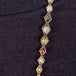 A close-up of a multi-colored graduated diamond necklace woven with 18k yellow gold chain throughout. 
