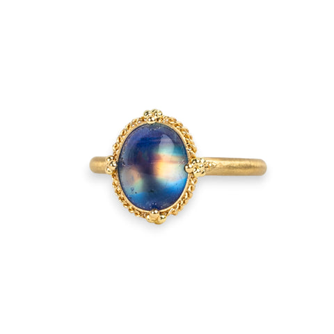 Moonstone ring in 18K yellow gold, with colors swirling akin to the Milky Way. Yellow and gold streaks through deep, navy blue. Set in a meticulously handmade gold frame with braided gold and granulated prongs. 