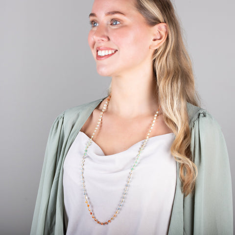 A model wears a long mixed-opal bead necklace featuring shades of burnt orange, teal and periwinkle woven with 18k yellow gold chain.
