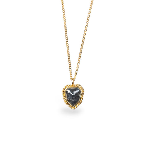 A black diamond pendant in 18k yellow gold bezel, suspended from an 18K yellow gold chain. Diamond evokes a cloudy night sky with star-like facets, set in a unique design with handmade gold bezel and braided detail. Handmade in New York.