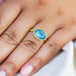 A model wears this Aquamarine ring in 18K yellow gold, evoking the mysterious depths of a deep blue sea. Handmade gold frame with delicate braided gold accents and granulated prongs. Handmade in New York. 