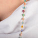 A close up of a multi-colored gemstone necklace set in 18k yellow gold. The stones include Aquamarine, Opal, apatite, Moonstone, Tanzanite, Carnelian, Tourmaline, Amazonite, Rhodochrosite, Chalcedony, and Jade