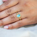 A model wears this Aquamarine ring in 18K yellow gold, featuring a misty blue oval gemstone reflecting a serene summer sky. Meticulously handmade gold bezel with braided gold accents and granulated prongs. Handmade in New York