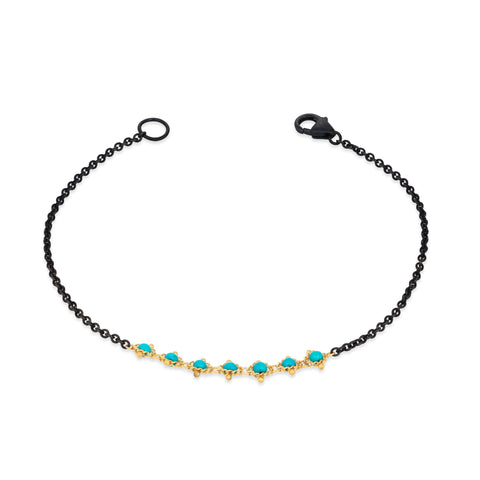 This oxidized sterling silver bracelet features a row of turquoise beads suspended in 18k yellow gold chain in the center.