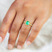 A model wears this Emerald ring in 18K yellow gold, capturing lush, vibrant green reminiscent of Spring sprouts. Intricate frame of shimmering golden chain and delicate beaded prongs. Handmade in New York.
