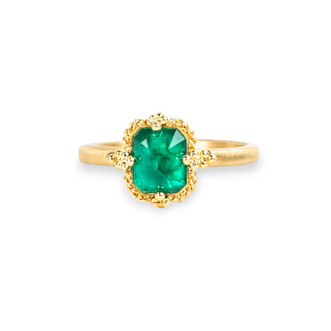 Emerald ring in 18K yellow gold, featuring lush, vibrant green reminiscent of Spring sprouts. Encased in an intricate frame of shimmering golden chain and delicate beaded prongs.