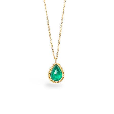 Emerald pendant with a glowing, perfect emerald green hue, suspended from an 18K yellow gold chain and set in a handmade gold bezel. Handmade in New York.