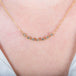 A close-up of a delicate 18k yellow gold chain necklace that features a row of woven grey diamond beads in the center