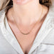 A model wears a delicate 18k yellow gold necklace with a row of woven grey diamond beads in the center.