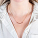 A model wears a delicate 18k yellow gold necklace with a row of woven ruby beads in the center.