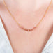 A close-up of a delicate 18k yellow gold chain necklace that features a row of woven spinel beads in the center