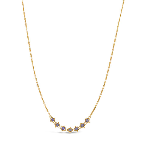 This delicate 18k yellow gold necklace features a row of seven woven tanzanite beads in the center. The necklace is finished with a lobster clasp closure
