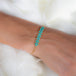 A model wears a delicate 18k yellow gold chain bracelet featuring three rows of woven turquoise beads in the center. The bracelet is finished with a lobster clasp closure.