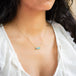 A model wears this Ethiopian Opal pendant on an 18K yellow gold chain. Handmade gold frame adorned with braided gold and granulated prongs. Handmade in New York. 