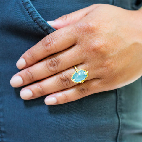 A model wears an oval aquamarine ring set in 18k yellow gold