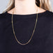 A model wears an 18k yellow gold chain necklace with rows of black diamond stations woven throughout.