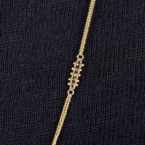 A model wears an 18k yellow gold chain necklace with rows of champagne diamond stations woven throughout.