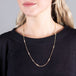 A model wears a long 18k yellow gold chain necklace with rows of silver diamond stations placed throughout the chain.