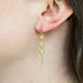 A model wears an opal trio earring suspended in 18k yellow gold chain.