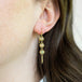 A close-up of an opal trio earring suspended in 18k yellow gold chain.