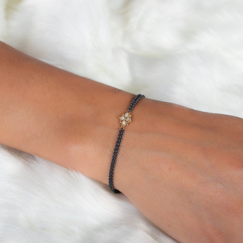A model wears an oxidized sterling silver bracelet with an 18k yellow gold and silver diamond lattice in the center.