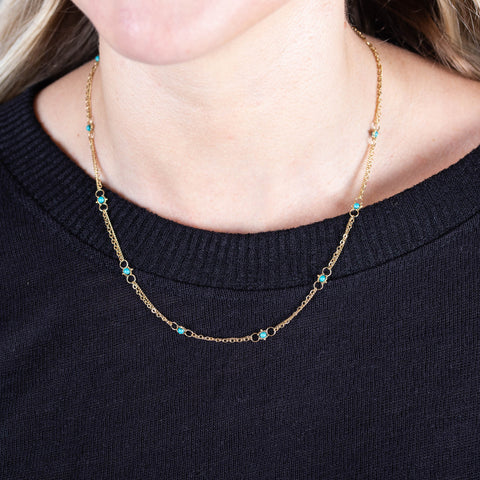 A model wears a short 18k yellow gold chain necklace dotted with turquoise beads throughout.