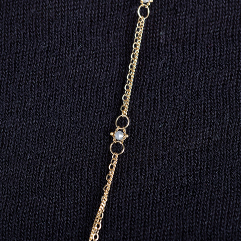 A close-up of a delicate woven 18k yellow gold chain necklace with a silver diamond bead station.