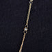A close-up of a delicate woven 18k yellow gold chain necklace with a silver diamond bead station.