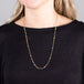 A model wears a long 18k yellow gold chain necklace dotted with silver diamond beads throughout.