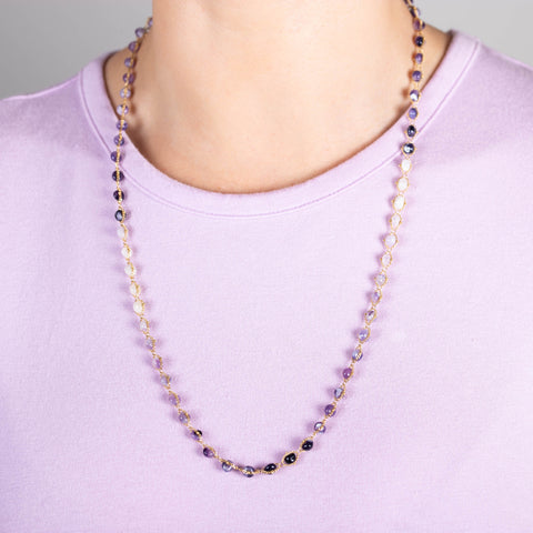 A model wears a long ombre shaded amethyst necklace, woven throughout 18k yellow gold chains.