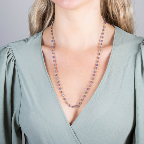 A model wears a long tanzanite bead necklace woven with 18k yellow gold chain.