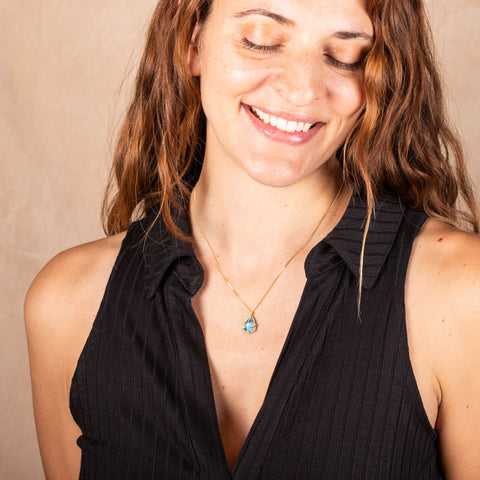 A model wears a small angular turquoise pendant set in 18k yellow gold on a small gold chain.