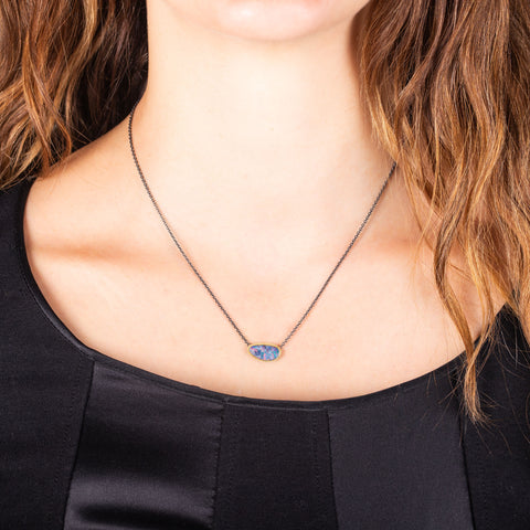 A small Australian opal pendant set in 18k yellow gold is on an oxidized sterling silver chain.