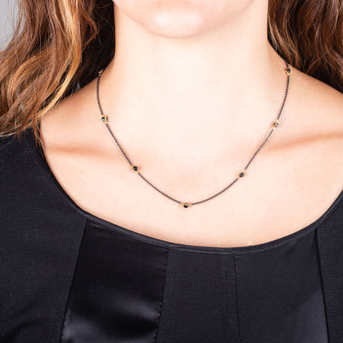 Several 18k yellow gold wrapped black diamonds are placed in an oxidized sterling silver chain.
