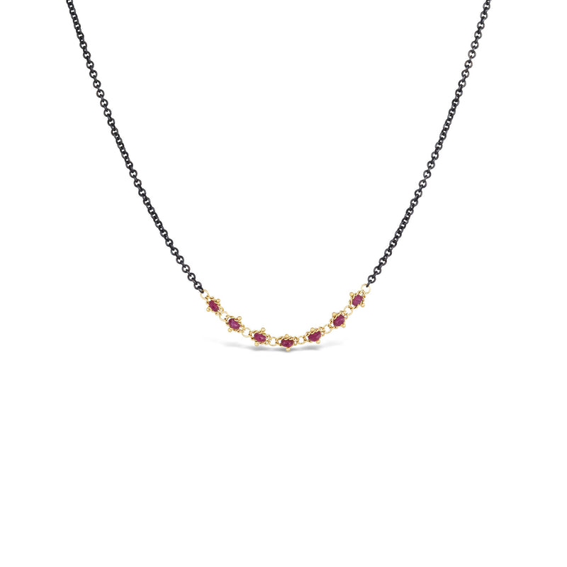 This short necklace is crafted with 18k yellow gold wrapped rubies in the center of an oxidized sterling silver chain.