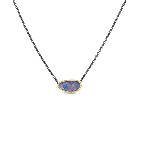 An elongated Australian opal with blue, pink and purple hues, is set in a handmade 18k yellow gold bezel on an oxidized sterling silver chain.