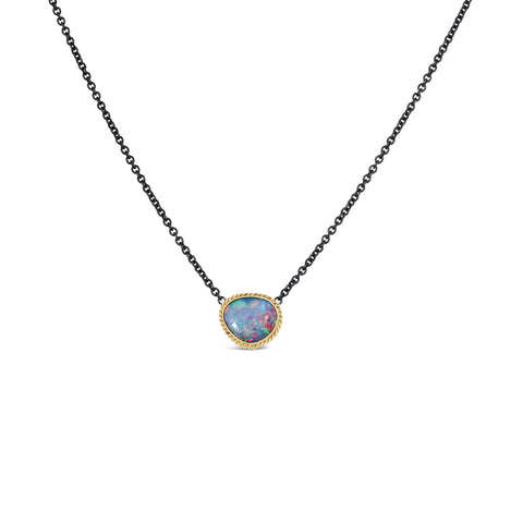 A small Australian opal with blue, pink and green hues is set in an 18k yellow gold bezel on an oxidized sterling silver chain.