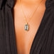 A vertical rectangular black diamond pendant is set in an 18k yellow gold chain wrapped bezel with four beaded prongs. The pendant is hanging on a delicate chain.
